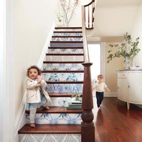 Arhaus children playing on blue and white wallpaper stairs